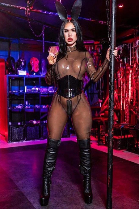 Angelina in her latex see through catsuit next to a pole 